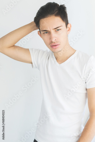 Portrait of a young man with dark hair and light eyes. on a white background. The guy in the white T-shirt. Male model.