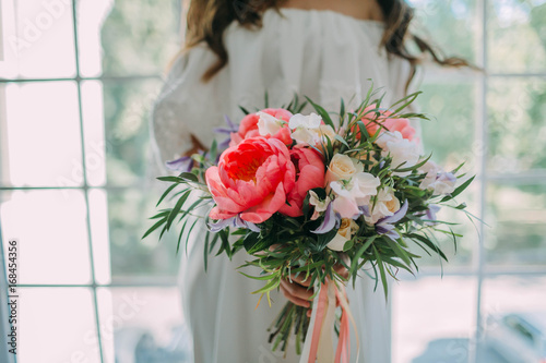 Wallpaper Mural Bride holds in hands a rustic wedding bouquet with white roses and crimson peonies on window background. Close-up Torontodigital.ca