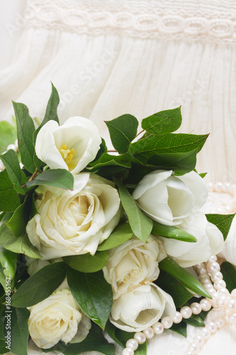 bunch of white fresh rose and tulips flowers with green leaves close up on white lace background