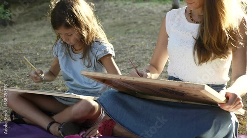 Woman with daughter drawing by watercolor paints at the park photo