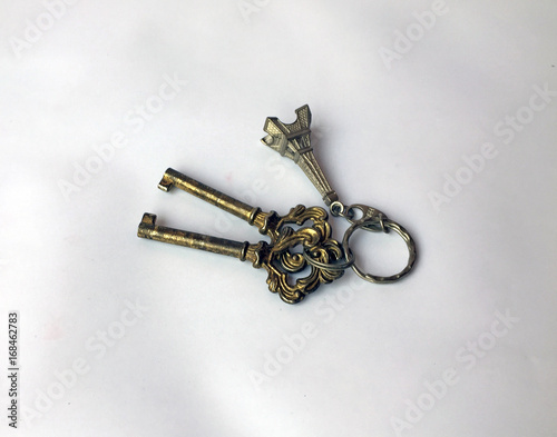 Two metal keys and Eiffel Tower key chain isolate on white background. the key is a small piece of shaped metal with incisions cut to fit the wards of a particular lock. © Achisatha