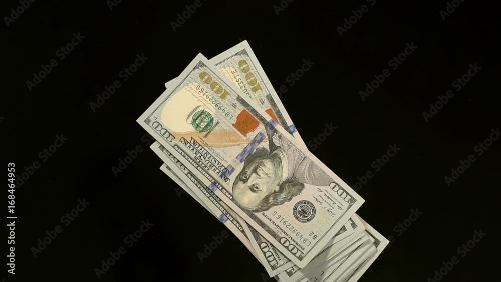 Lot of 100 dollar bills on a black mirrored background, close-up. Stack of hundred dollar bills falling on table. Lot of 100 dollar bills on a black mirrored background, close-up. Stack of hundred dollar bills falling on table.