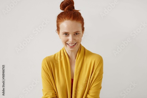 Joy, fun and happiness concept. Attractive happy young European casually dressed lady wearing her ginger hair in knot feeling relaxed and carefree, spenidng lesiure time at home on her day-off photo