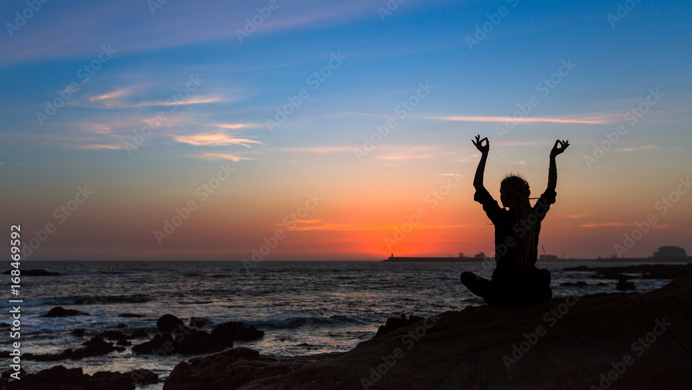 Yoga silhouette woman on the Sea during sunset.