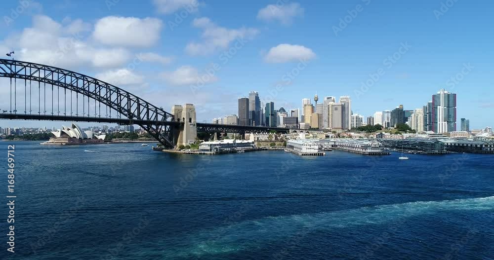 Descending in view of The Rocks and distant Sydney city CBD with arch of the Sydney Harbour Bridge to shore of Blues Point on a sunny day. Descending in view of The Rocks and distant Sydney city CBD with arch of the Sydney Harbour Bridge to shore of Blues Point on a sunny day.