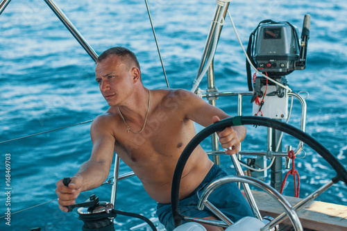 Young man at the helm of a sailing yacht. © De Visu