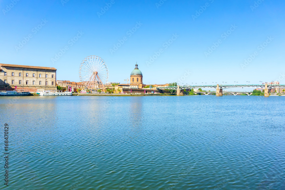 Ferris Wheel and view of Saint-Pierre Bridge over Garonne river and Dome de la Grave in Toulouse, France