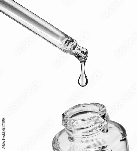 Drop falls from a pipette into a cosmetic bottle,isolated on white background photo