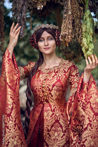 Beautiful Isabella of France, queen of England on Middle Ages period in red gown near medieval castle photo