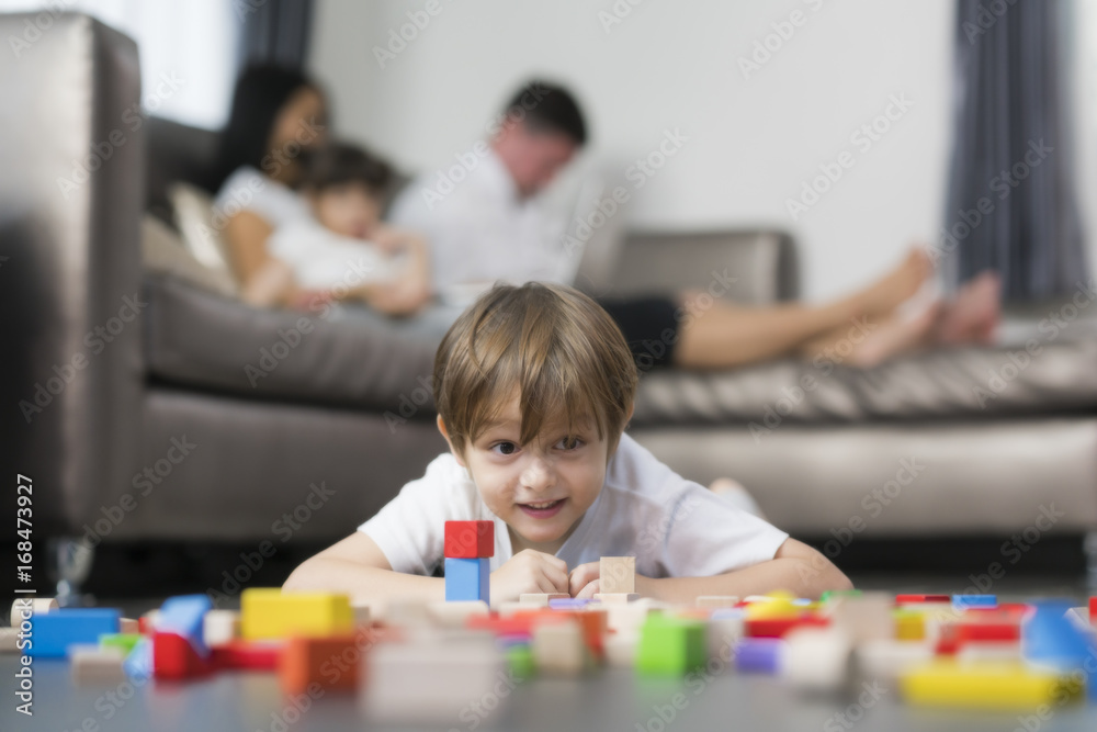 Fototapeta premium Caucasian boy play wooded toy in living room in home with his father and mother