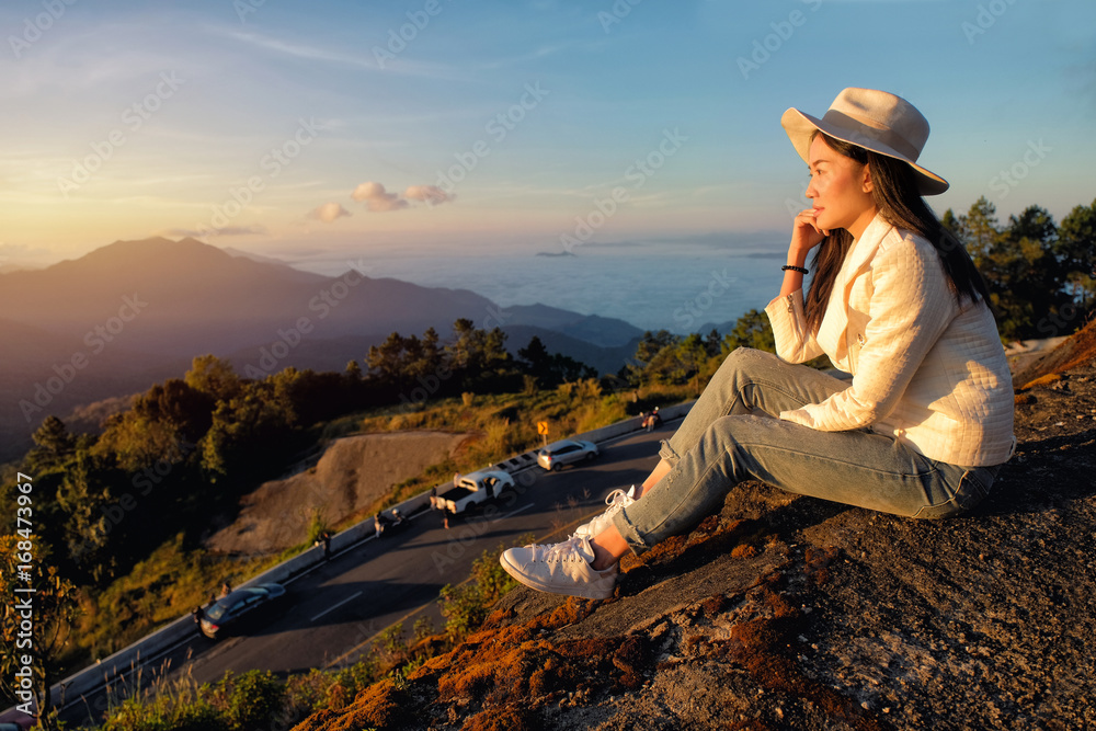Woman siting on the hill and enjoying beautilful nature sunrise in winter in Chiang Mai, Thailand