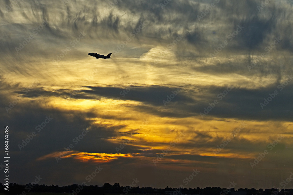 Aeroplane (airplane) taking off at sunset.