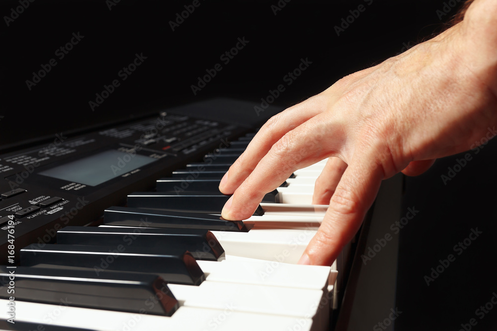 Hand of musician play the keys of the electronic organ on a black background Hand of musician play the keys of the electronic organ on a black background