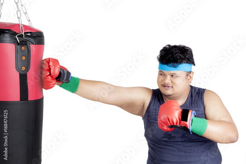 Overweight man punching boxing sack © Creativa Images