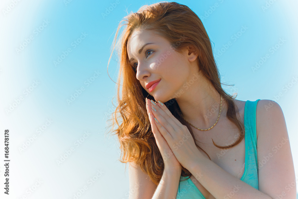 Closeup portrait of a young woman praying. Pray in the Morning , Woman praying with hands together on blue background. Believers meditates in the cathedral. Spiritual time of prayer.