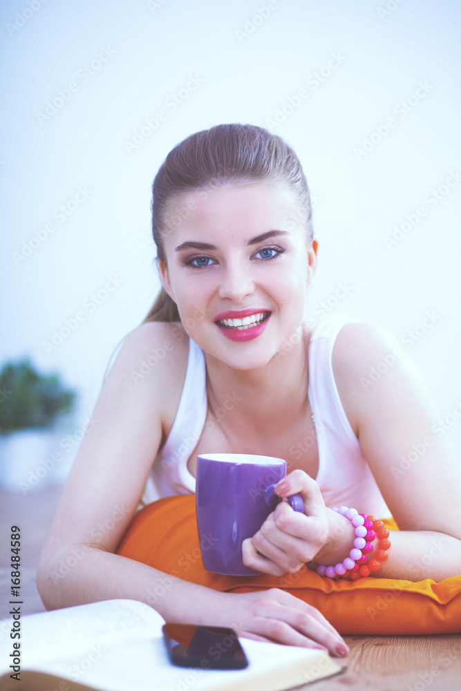 Smiling young woman lying on a white floor with pillow Smiling young woman lying on a white floor with pillow