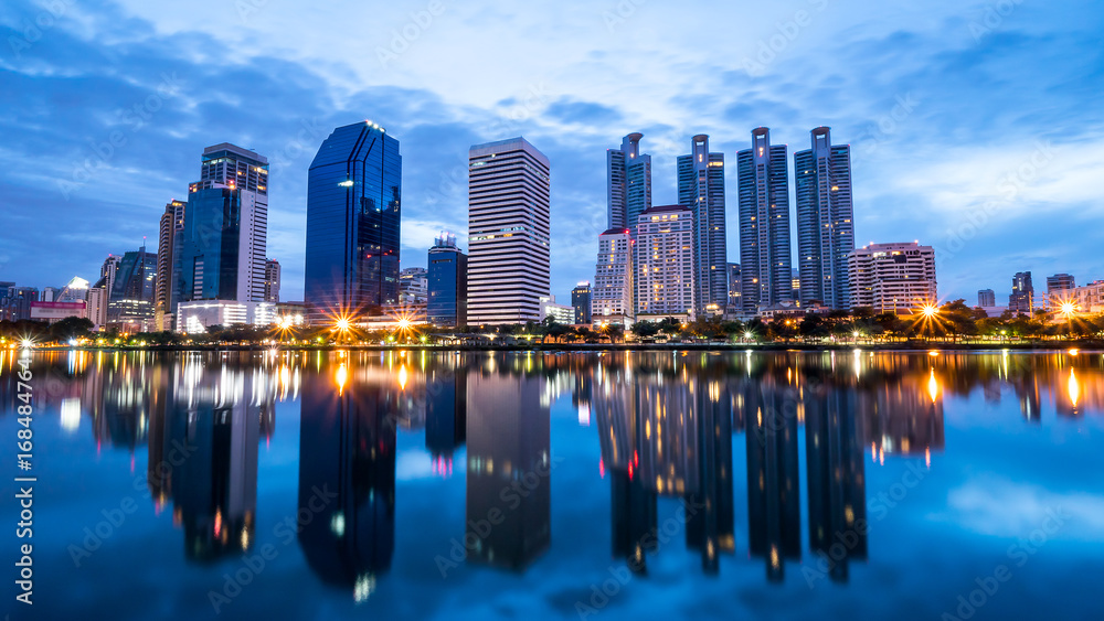 Night light cityscape view with modern building in the park beside lake at Bangkok, Thailand (Blue color tone)