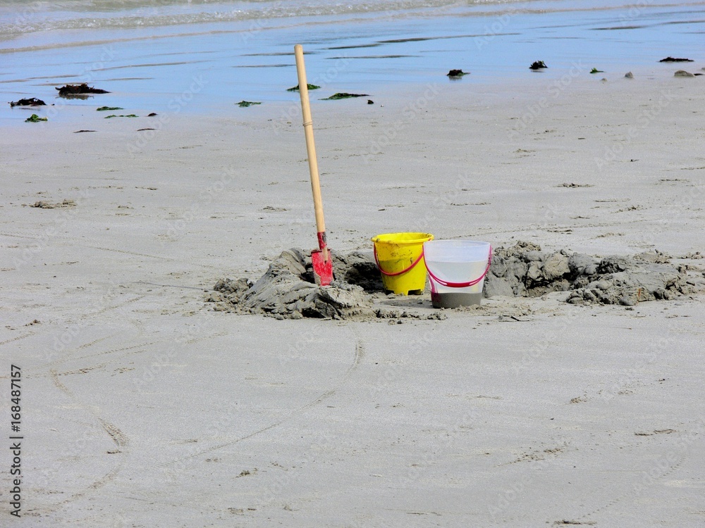 Naklejka premium Une pelle et deux seaux sur une plage de sable