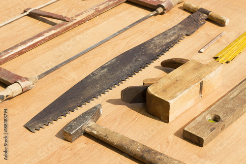 Stare narzędzia stolarskie leżą poukładane na stole. 
