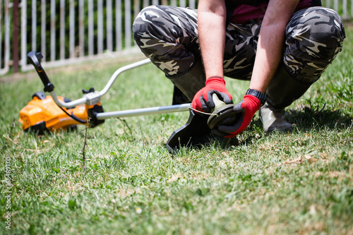 Man working with grass trimmer in home yard or garden