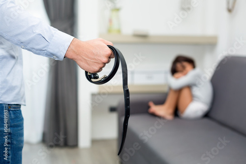 Parents abuse the child, girl fearing at her father, selective focus at belt © Getty Gallery