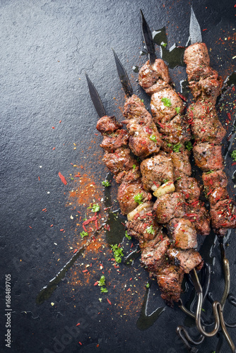 Traditional Russian shashlik on a barbecue skewer as top view on a board