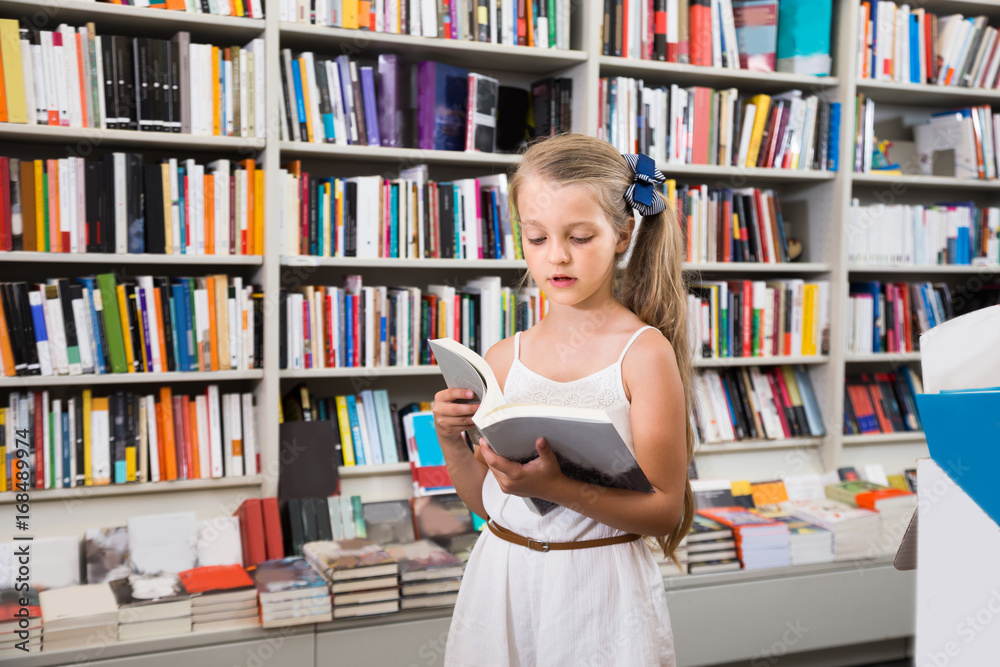 girl child considers the book in a bookstore girl child considers the book in a bookstore