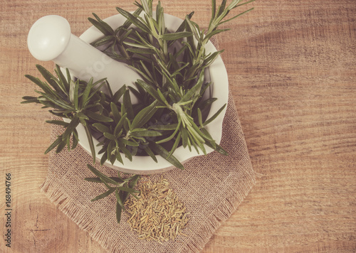 Fresh raw and dry rosemary on rustic background.