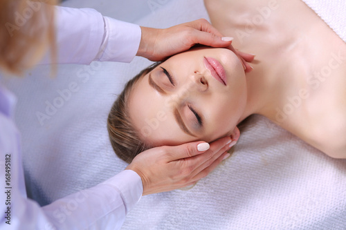 Young woman lying on a massage table,relaxing with eyes closed. Woman. Spa salon