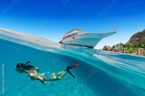 Small safari boat with snorkeling woman underwater.