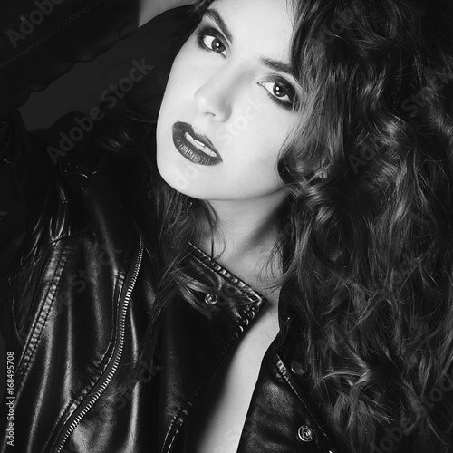 Beautiful young woman posing in black leather jacket over grey background. Fashion concept.
