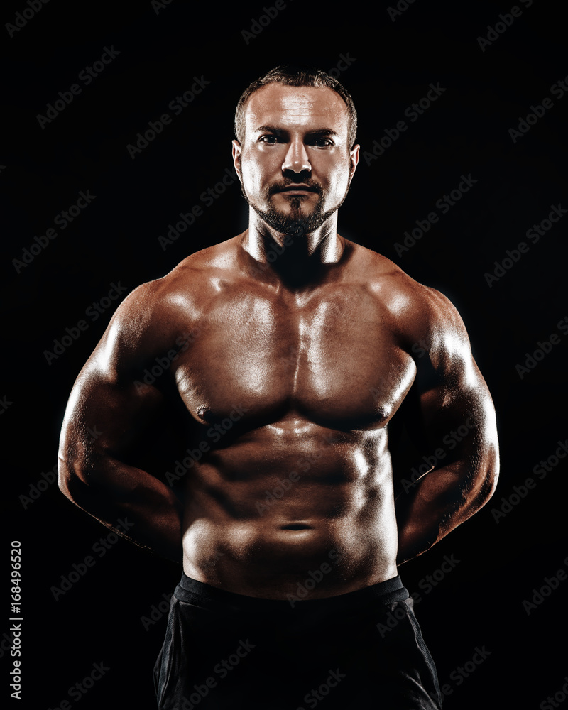 Strong athletic bodybuilder with six pack, perfect abs, shoulders, biceps, and triceps chest, personal fitness trainer flexing his muscles Strong athletic bodybuilder with six pack, perfect abs, shoulders, biceps, and triceps chest, personal fitness trainer flexing his muscles