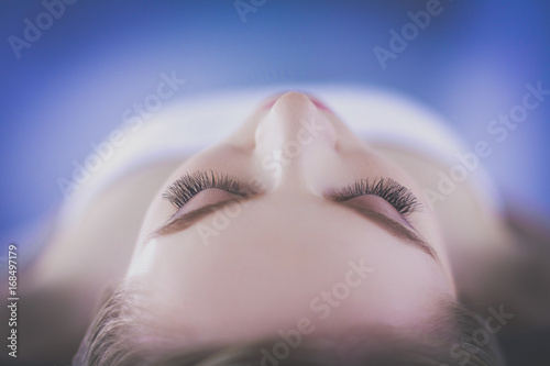 Young woman lying on a massage table,relaxing with eyes closed. Woman. Spa salon