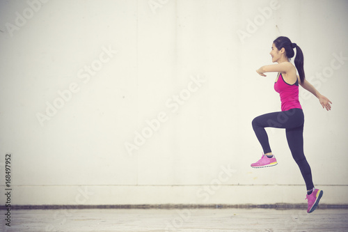 Side view shot of fit young woman doing cardio interval training against grey background. Fitness female exercising outdoors in morning.Vintage color
