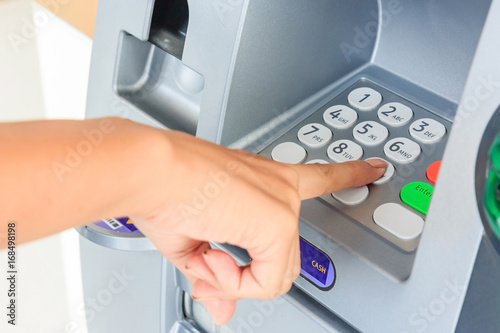 Close up of hand entering pin at an ATM. Finger about to press a pin code on a pad. Security code on an Automated Teller