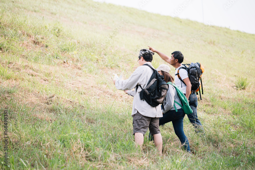 Group of backpacking hikers going to mountain top and navigating by map. Backpackers or Hikers travel concept. Selective focus.