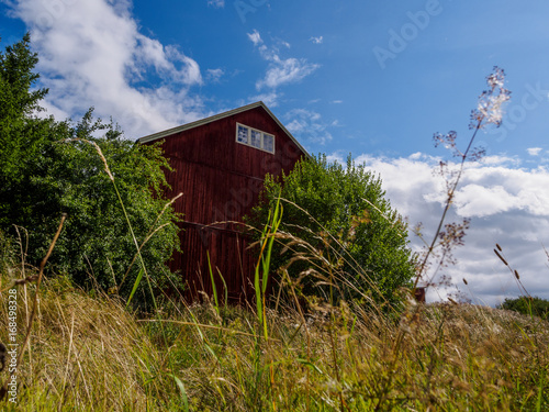 Red wooden farm building against blue cloudy sky