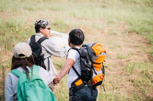 Group of backpacking hikers going to mountain top and navigating by map. Backpackers or Hikers travel concept. Selective focus.