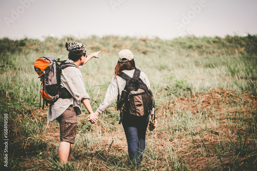 Couple of backpacking hikers going to mountain top and navigating by map paper. Backpackers or Hikers travel concept. Selective focus and vintage tone.