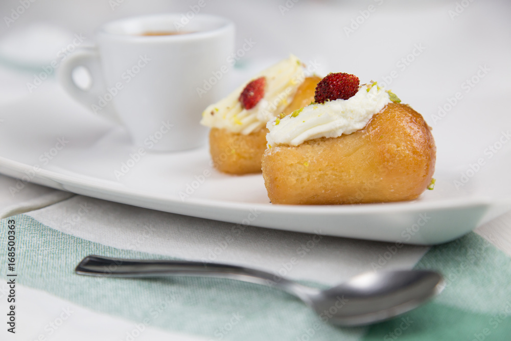Neapolitan babà and coffee on white white dish Neapolitan babà and coffee on white white dish