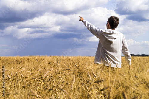 Man in a wheat field showing his fingers in the direction of the sky © mk1ne