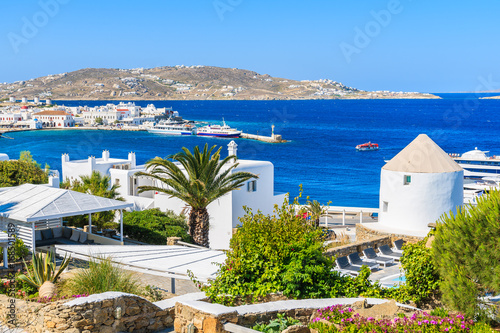 View of Mykonos sea bay with palm tree and windmill in foreground, Mykonos island, Greece