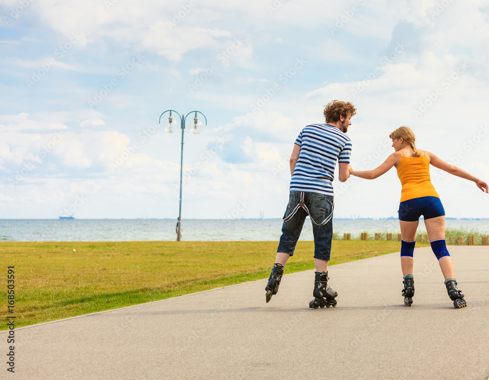 Young couple on roller skates riding outdoors Young couple on roller skates riding outdoors