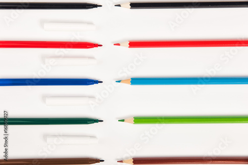 Colored markers pattern on white background. Line of coloured drawing pencils. Top view.