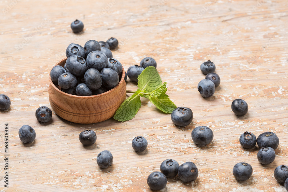 Black ripe berries lie on a wooden saucer and scattered on an old board Black ripe berries lie on a wooden saucer and scattered on an old board