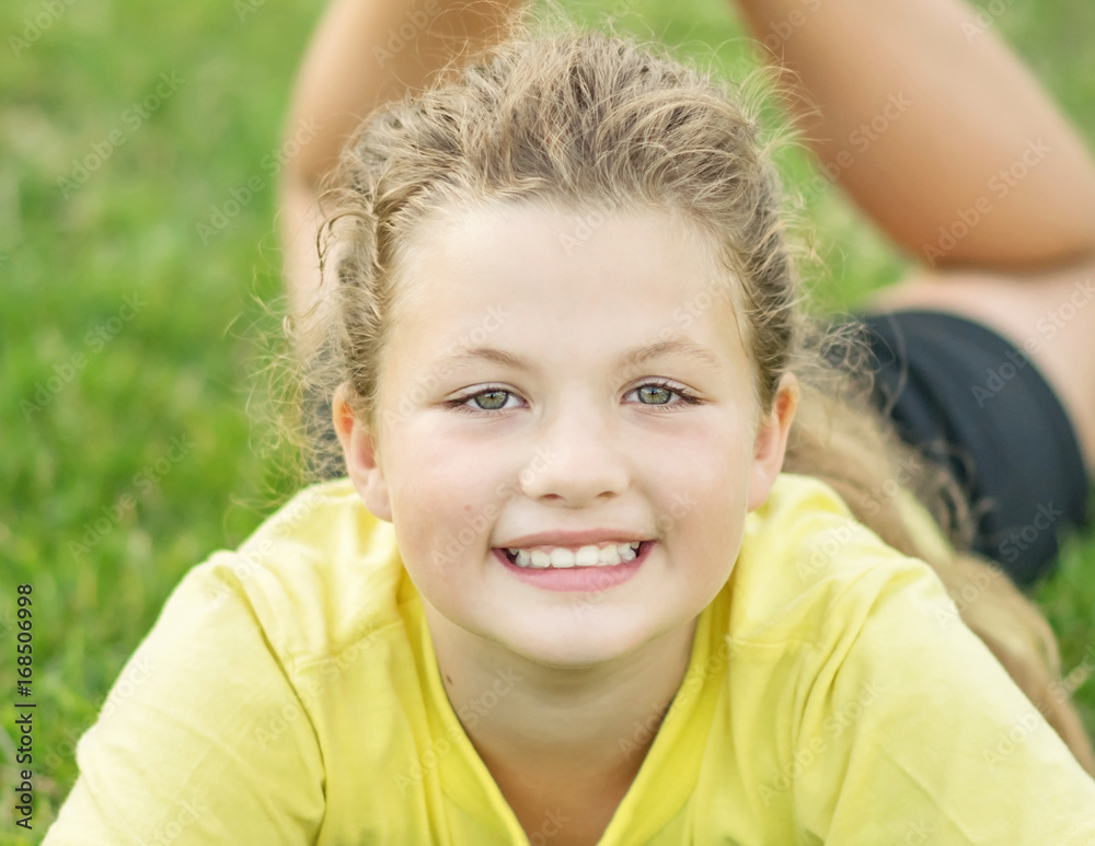 A young, pretty little smiling girl with long hair doing exercises outdoor A young, pretty little smiling girl with long hair doing exercises outdoor