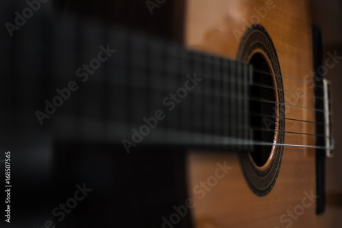 Acoustic guitar background, unusual view. Blurred photography, selective focus. Copyspace, perfect as wallpaper or backdrop for design, poster, flyer or prints.