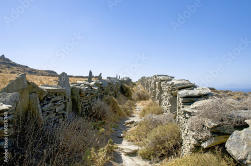 In Steinmauern gefasster Weg auf karger griechischer Insel unter blauem Himmel im Herbst