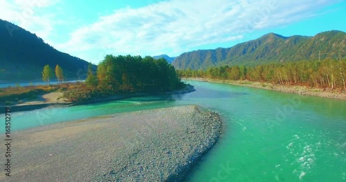 4k (UHD) aerial view. Low flight over fresh cold mountain river at cloudy summer morning. Green trees and sun rays on horisont. Fast horizontal movement