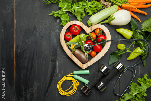 Fresh vegetables. Diet, a healthy lifestyle. Sport, dumbbells and skipping rope on a black background
